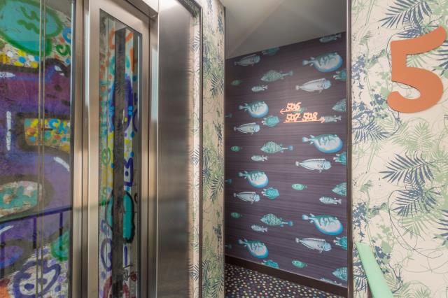 Papiers peints et signalétique colorés aux abords de l'ascenseur de l'hôtel Exquis, à Paris (11e).