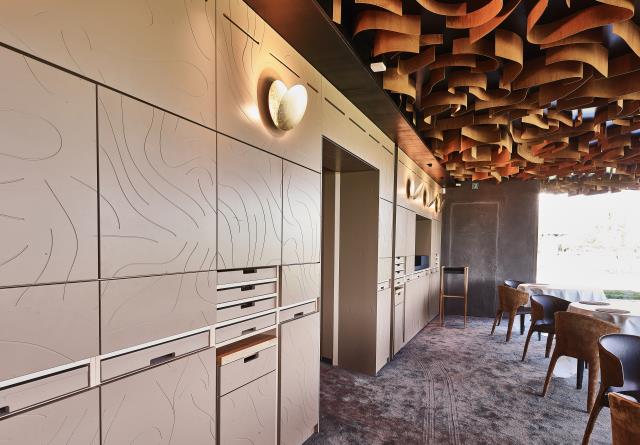Un mur de tiroirs, rangements et tablettes dans la salle de restaurant.