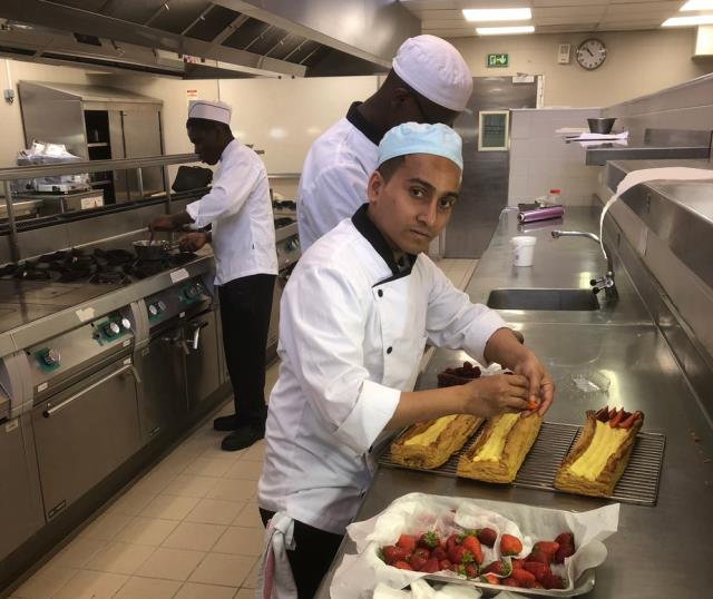 Un jeune apprenti prérarant la Bande feuilletée, mousseline pistache aux saveurs du botaniste Frézier