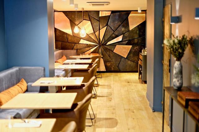 Avec des matières comme le cuivre et le bois recyclé, le décor aux teintes bleus et beiges s'allie avec la modernité des plats