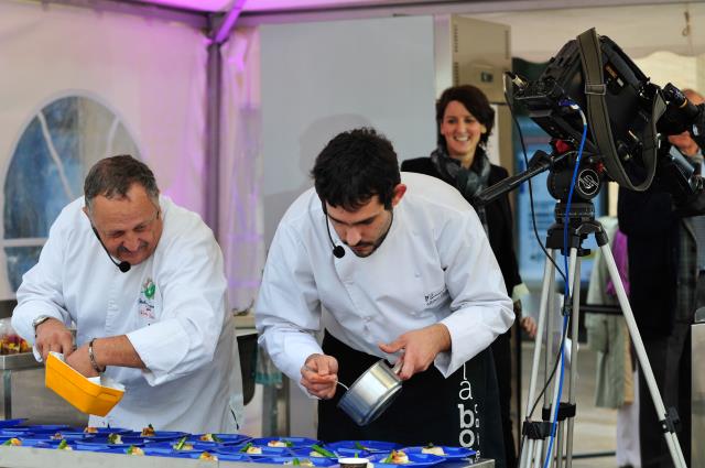 Légende : René Bergès et Miguel Marin de Espinosa, ont notamment préparé du cabillaud à l'huile d'olive avec son ragoût de tripes et asperges sautées et pain brûlé de mangue et crumble de biscuits Maria, sous le regard avisé d'Anne Limbour, chroniqueuse c