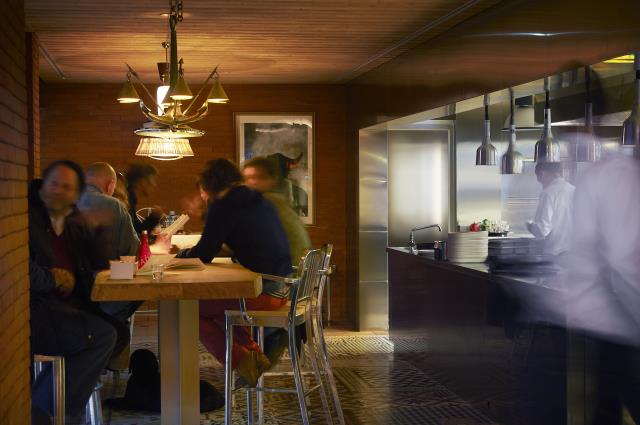 Une longue table d'hôtes face à la cuisine ouverte.