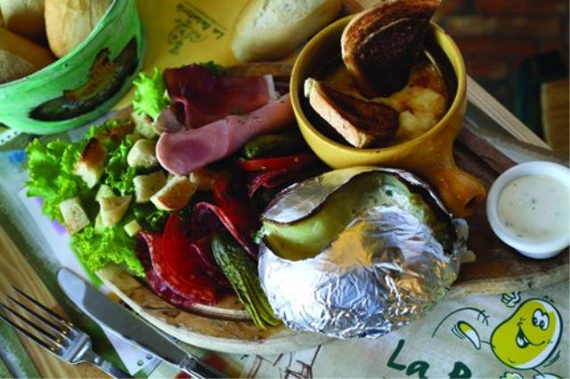 Pom's au four Savoyarde (pomme de terre cuite au four, jambon cru, jambon cuit, fromage à raclette fondu, cornichons, sauce fines herbes et salade mêlée).