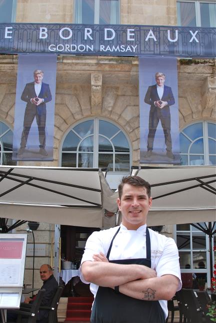 Alex Thiebaut (premier plan) devant la brasserie Le Bordeaux Gordon Ramsay bien identifiée avec les grandes photos du chef écossais multiétoilé