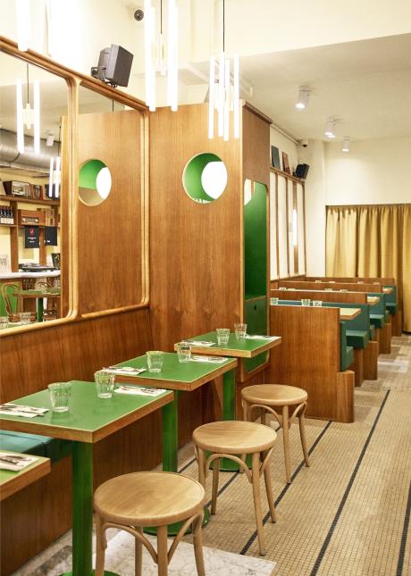 Un décor contemporain, teinté de références vintage : miroirs en bois arrondi et banquettes en cuir vert emblématique des 70's.