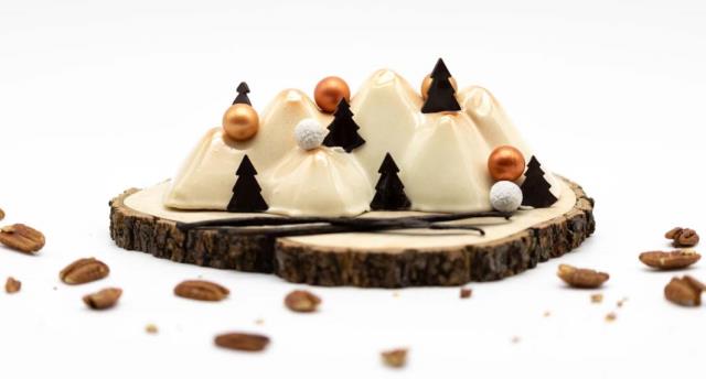 Évocatrice des monts enneigés, de l'odeur des pins, des boules de neiges et de feu qui crépite dans l'âtre de la cheminée, la Bûche Monts et Merveilles des Hôtels Barrière est signée Christophe Adam et produite par Benjamin Siwek, chef pâtissier de Traite