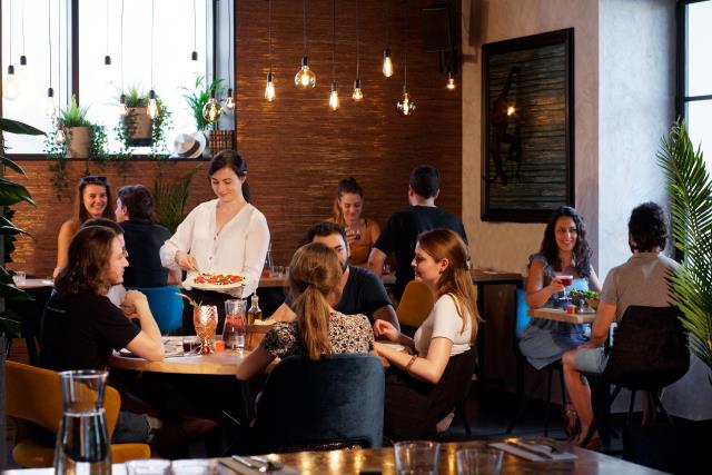 Les serveurs proposent à table des pizzas à la part.