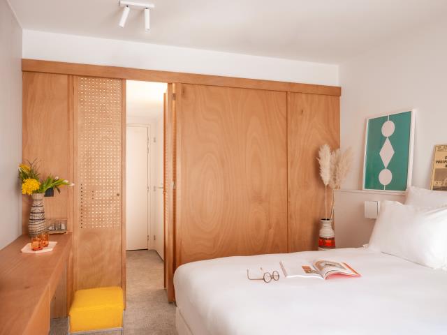 Dans les chambres, rideaux, panneaux en bois d’okoumé et éléments de déco colorés contrastent avec les murs clairs