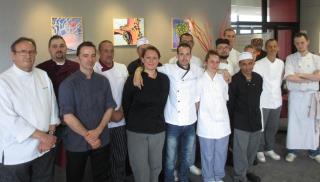 Les douze adultes candidats entourés des cuisiniers membres du jury.