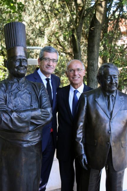 Dominique Giraudier et Hervé Fleury, aux côtés des statuettes de Paul Bocuse et GGérard Pélisson à l'Institut Paul Bocuse d'Ecully (69).