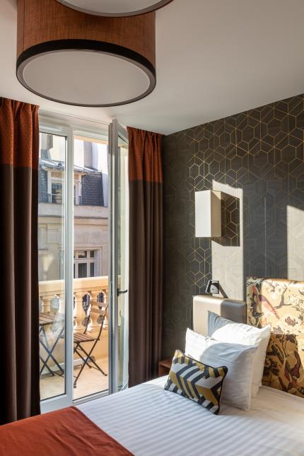 De l'art d'accorder les motifs graphiques d'un coussin ou d'un papier peint avec les imrpimés fleuris d'une tête de lit.