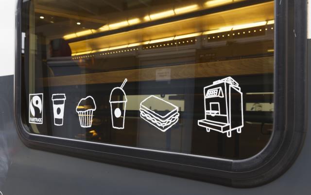 Des icônes blanches illustrant boissons et muffins ainsi que le symbole Fairtrade et une photo de machines espresso Starbucks ont été créés et placés sur les fenêtres afin de mettre en avant l'offre à disposition.