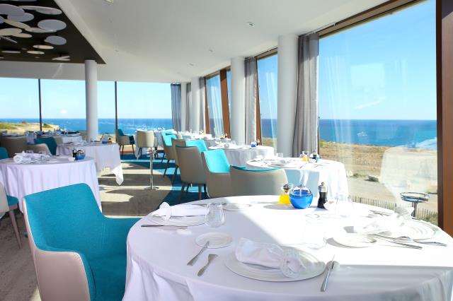 La salle du restaurant, avec une large vue ouverte sur la falaise et la mer