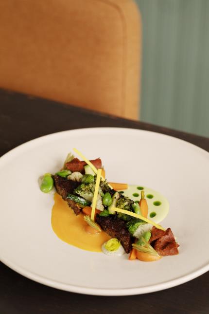 Un plat de Stéphane Enault: tempeh de quinoa, légumes primeurs, pousses d'épicéa fermentées, pastrami végétal, crème de petit pois et sauce carotte - vinaigre de pin