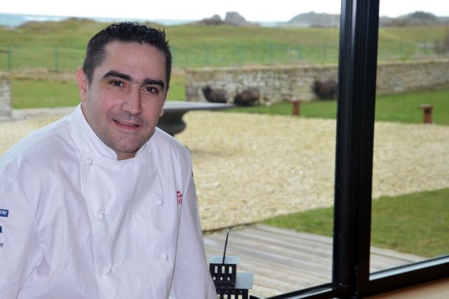 Le Chef étoilé Julien Marseault dans la salle du restaurant avec vue sur la presqu'île Saint Laurent et les moutons d'ouessant