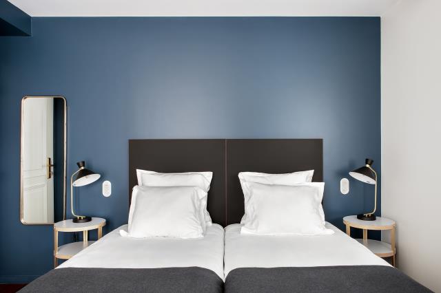 Chambre fraîchement rénovée du New Hotel Le Voltaire à Paris (XIe), avec tonalité colorée sur les murs et chevets signés Kostia.