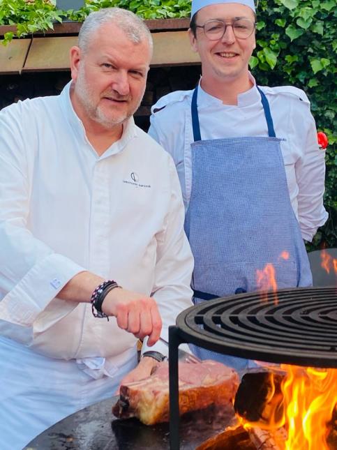 Le chef étoilé Christophe Dufossé  et le boucher Franck Charlet en cuisine, au feu de bois, sur la terrasse de la brasserie du Château de Beaulieu.