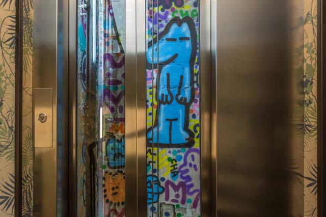 Les murs de la cage d'ascenseur de l'hôtel Exquis, à Paris (11e), recouverts de graffs.