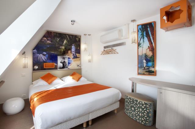 Le blanc immaculé de la chambre est souligné par des touches de couleur orange.