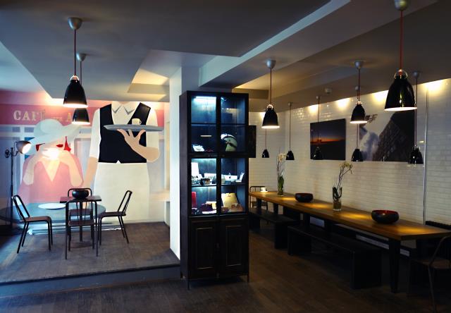 Dans le lobby ont été aménagés un petit salon et un petit meuble où sont présentées les créations originales d'une nouvelle artiste. À droite, la table d'hôtes a été réalisée par les ateliers de décors Mirific.