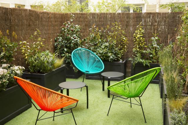 Le petit jardin intérieur équipé de chaises aux couleurs vives est une invitation à se détendre.