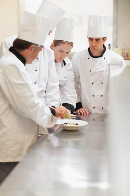 L'équipe écoute attentivement le chef qui leur présente le menu du jour.