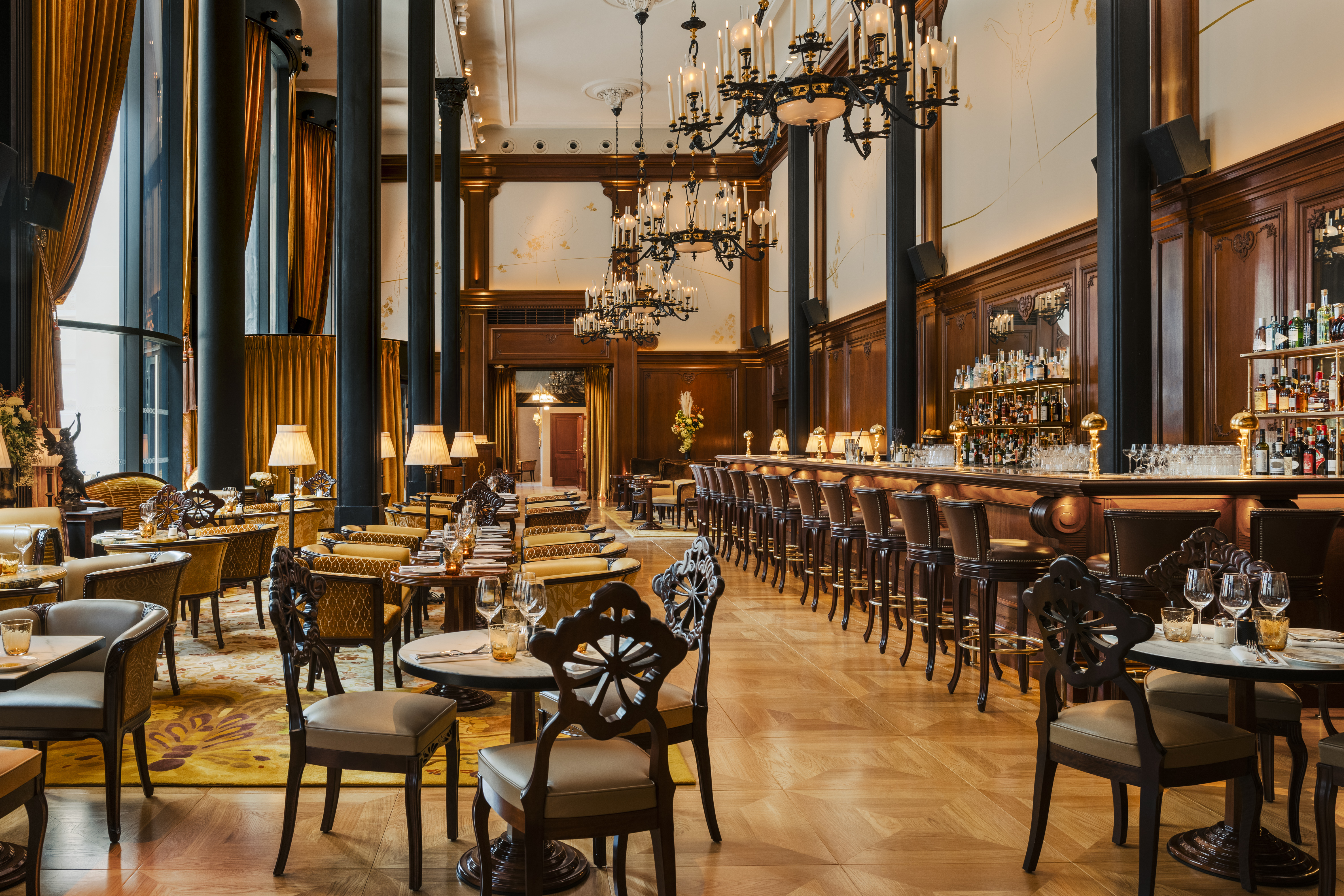 Grande hauteur sous plafond, lustres chandeliers, fresques sur les murs dans la salle Belle-Epoque du Madame Rêve Café.