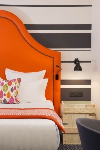 L'ambiance lumineuse sont des éléments constitutifs de l'aménagement de la chambre. Ici, la table de chevet n'accueille aucun pied de lampe car celle-ci a été fixée au mur, ce qui facilite l'entretien. Le sol rappel la couleur du mur. L'Hôtel Fabric à Paris.