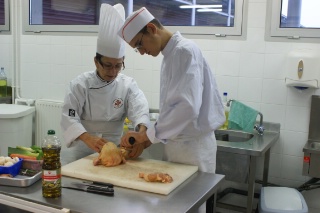 Viviane Darroze, professeur de cuisine, initie un des élèves à la découpe d'un poulet.