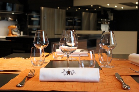 Un dressage de table simple : set de table, serviette blanche roulée, verres à eau et à vin et couverts de base.