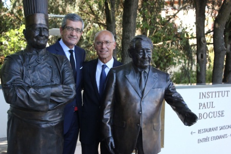 Dominique Giraudier et Hervé Fleury, aux côtés des statuettes de Paul Bocuse et Gérard Pélisson à l'Institut Paul Bocuse d'Ecully (69).