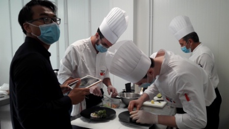 Chen Peng, manager Asie, traduit en direct les consignes de Jean-François Laroussarie et deux apprentis (Basile et Victor) sur la recette du 'Carpaccio de langoustines truffes d'été'.