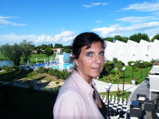 la directrice Fabienne Busson, avec au fond la terrasse du restaurant, la piscine et le golf.