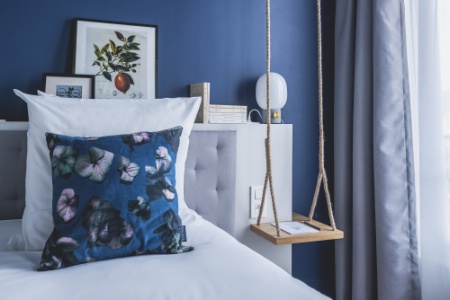 Détails : une balançoire en table de chevet, un herbier, un coussin fleuri.