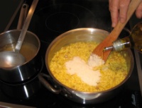 7. Une fois le risotto cuit, vérifier l’assaisonnement et ajouter du parmesan gratté et de l’huile d’olive, puis remuer énergiquement.