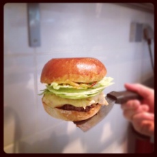 Hamburger Cheesy : boeuf, bun nature, cheddar anglais, bacon, sauce barbecue maison, oignon, pickles, salade iceberg.