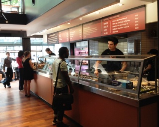 Devant un long comptoir, les clients choisissent leur plat, l'accompagnement, et assistent à la préparation expresse de leur repas.