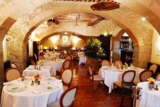 La salle du restaurant : pierres blondes et jarres de fleurs.