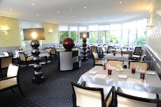 La salle du restaurant avec de larges baies vitrées qui donnent sur le jardin et les terrasses.