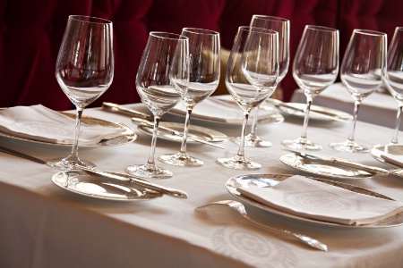 Le dressage de table est épuré : nappe blanche, assiette de présentation Haviland, couverts en argent, et verres en cristal Baccarat.