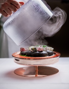 Bas en cuivre, des galets chauffés à 250 degrés sur lesquels sont disposées 5 bouchées différentes de poisson. Un bouillon au citron est versé sur les bouchées puis la cloche refermant le plat se remplit de fumée. Quelques secondes plus tard, on décloche, les bouchées sont cuites.