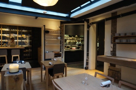 Du blanc, du noir et du bois : une salle épurée avec vue sur la cuisine.