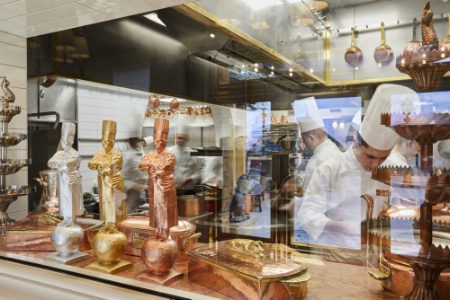 Dès l'entrée du restaurant, vue sur la cuisine et les statuettes du Bocuse d'or.
