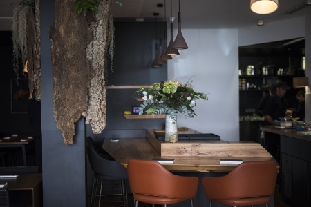 Dans un espace à la décoration minimaliste, tons noirs et blancs et éléments en bois, les clients se concentrent sur la succession de plats.