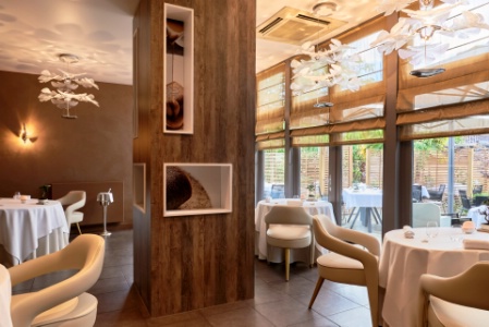 La salle aux teintes sobres et au design élégant s'ouvre sur une terrasse arborée à l'atmosphère contemporaine.