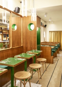 Un décor contemporain, teinté de références vintage : miroirs en bois arrondi et banquettes en cuir vert emblématique des 70's.